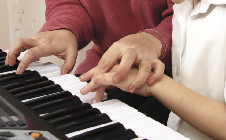 Women teaching youth to play piano