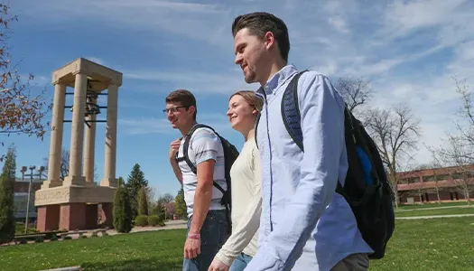 students walk across campus on a sunny day